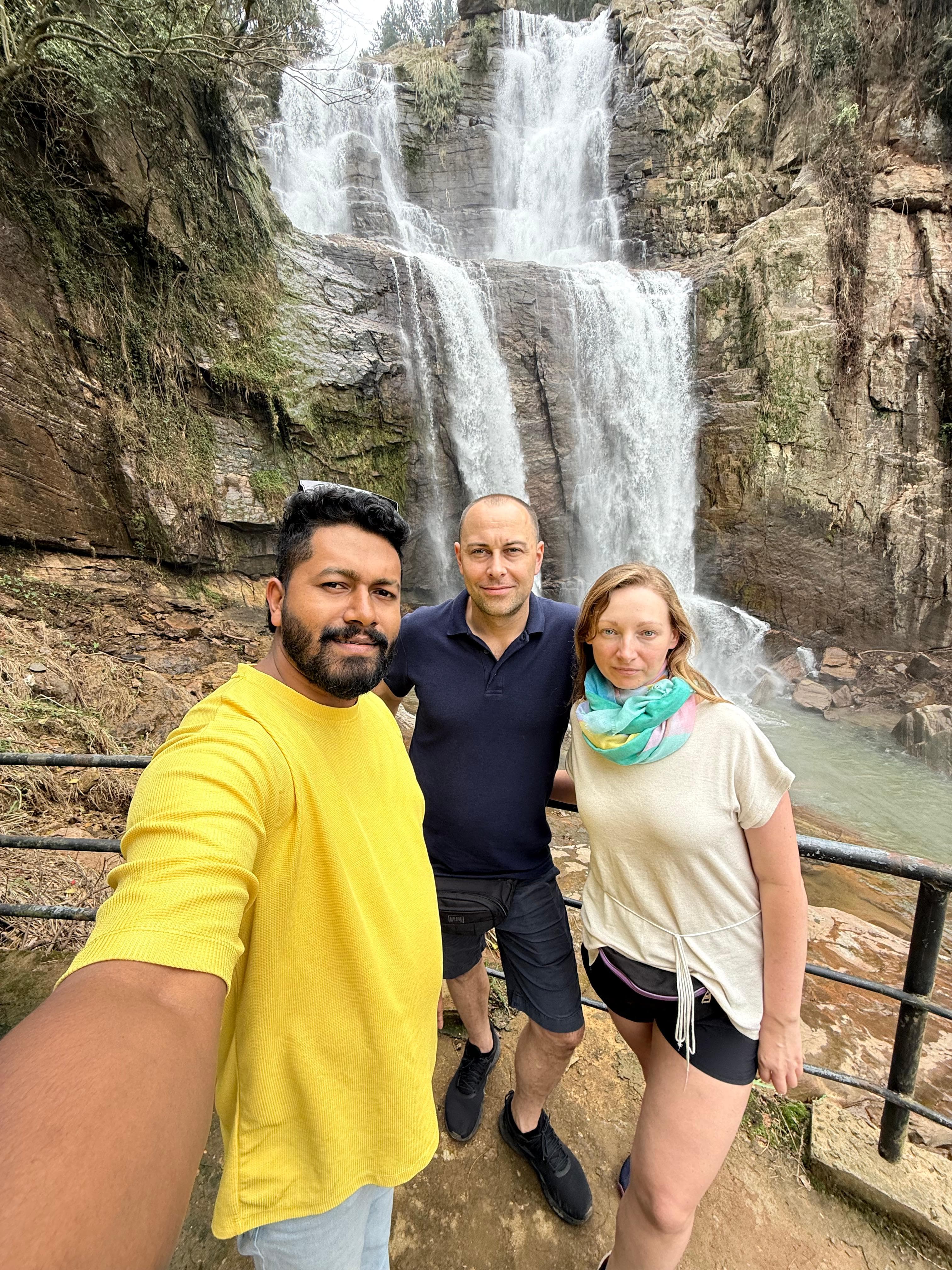 Guide and couple taking a waterfall selfie