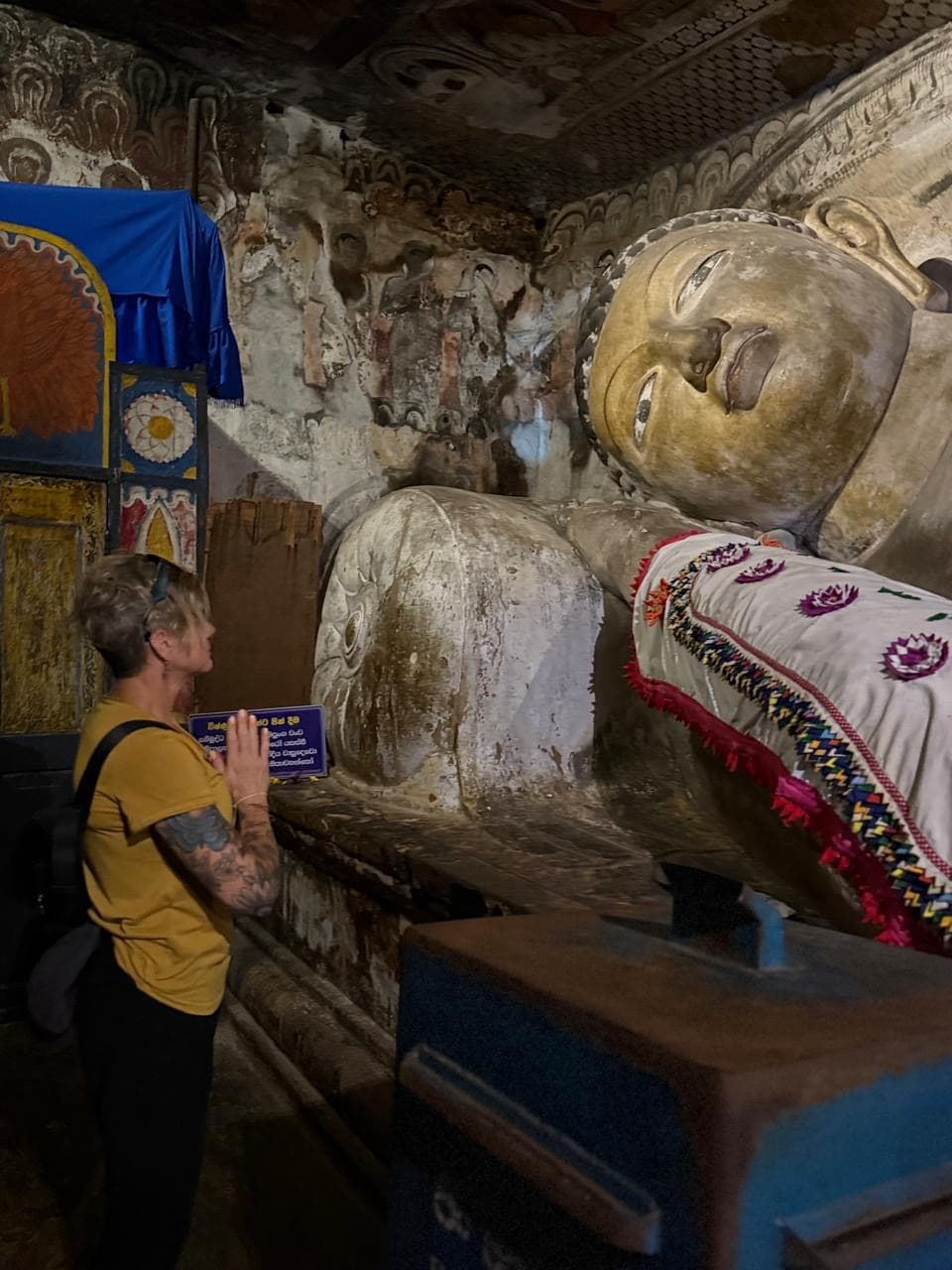 Woman in prayer before a reclining Buddha statue